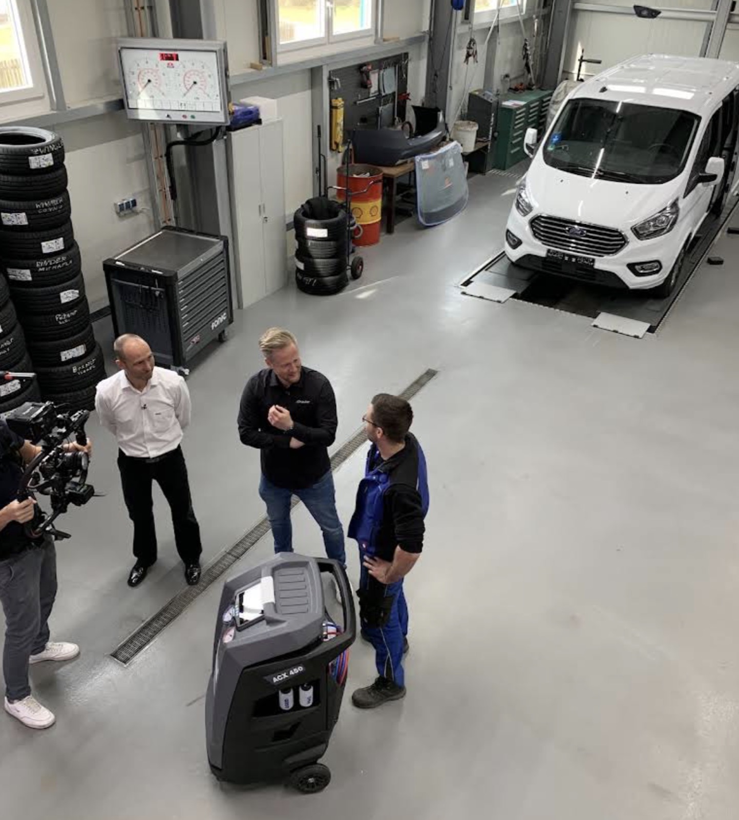 Blick in die Werkstatthalle mit Prüfstraße, eingelagerten Reifen und einem Ford Transit auf der Prüfspur